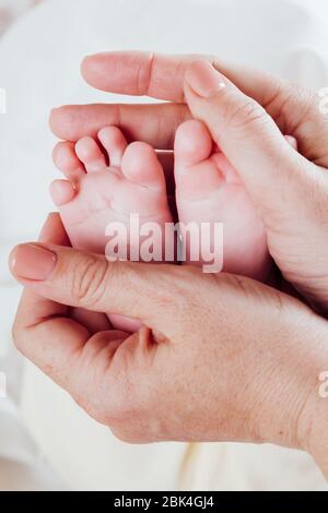 le mani della mamma tengono i piedi ai bambini Foto Stock