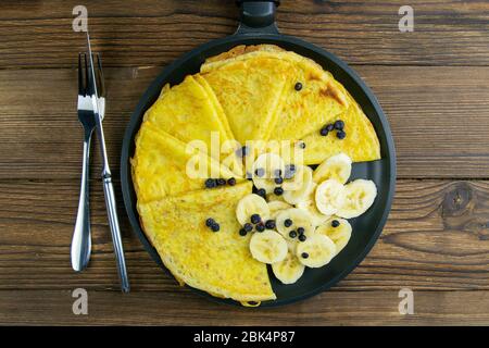 Gustosi pancake con banane e mirtilli su padella nera. Vista in primo piano. Pancake fatti in casa. Pancake colazione cibo Foto Stock