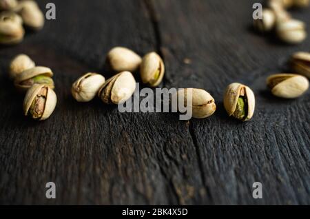 Pistacchi sparsi sul tavolo in legno vintage. Il pistacchio è un alimento nutriente sano della proteina vegetariana. Pistacchi su legno antico rustico. Foto Stock