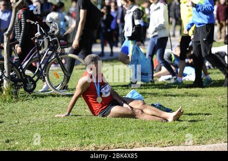 VALENCIA, SPAGNA - 1 DICEMBRE 2019: Maratona popolare Runner riposato sull'erba Foto Stock