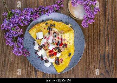 Gustosi pancake con banane, mirtilli e miele su piatto blu. Vista in primo piano. Pancake fatti in casa. Pancake colazione cibo Foto Stock