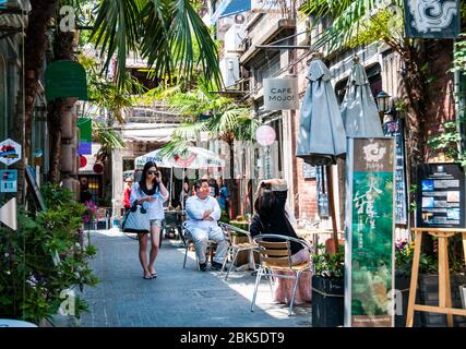 Un giovane cinese di moda donna cammina passato il caffè nella corsia 248 di Tianzifang, Shanghai, Cina. Foto Stock