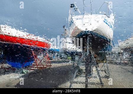 Kiel, Germania. 1 maggio 2020. Le barche a vela possono essere viste dietro un vetro coperto da gocce di pioggia nel porto olimpico di Kiel-Schilksee. Dal 4 maggio, i porti turistici di Schleswig-Holstein saranno riaperti. Dotati di maschera facciale, i proprietari di imbarcazioni private possono quindi gru le loro barche. Anche i residenti non appartenenti allo Schleswig-Holstein possono tornare. Credit: Frank Molter/dpa/Alamy Live News Foto Stock