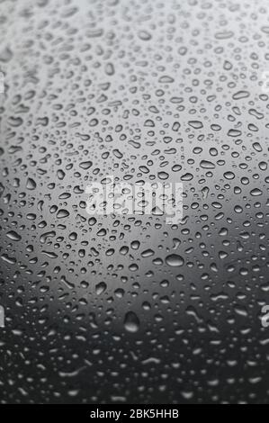 Foto ritratto di gocce d'acqua sparse su una superficie liscia in acciaio inox Foto Stock