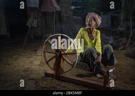 Ubud, Gianyar, Bali, Indonesia - 28 giugno 2019 : Antica donna balinese con la sua ruota rotante in un piccolo villaggio vicino a Ubud. Foto Stock