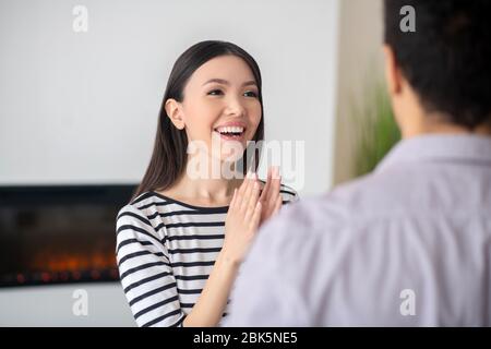 Giovane donna felice che le batte le mani davanti al marito. Foto Stock