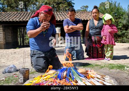 Sciamano che esegue una cerimonia di guarigione Maya per una famiglia sulla cima della collina Pascual Abaj, dove si trova la pietra sacra. Alcune fonti indicano Th Foto Stock