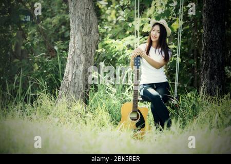 Bella giovane donna con chitarra acustica sullo sfondo della natura Foto Stock