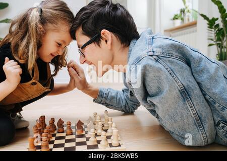 Concetto di competizione amichevole. Papà e dau che giocano a scacchi e teste di batting Foto Stock