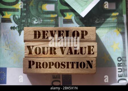 Sviluppa la tua proposta di valore su blocchi di legno in piedi su 100 euro fatture. Concetto di marketing aziendale Foto Stock