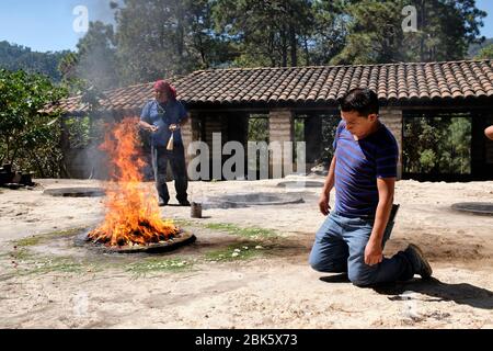 Sciamano che esegue una cerimonia di guarigione Maya per una famiglia sulla cima della collina Pascual Abaj, dove si trova la pietra sacra. Alcune fonti indicano Th Foto Stock