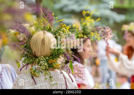 Donne non identificate in abiti tradizionali con solstizio estivo in fiori da campo, erbe e cereali. Foto Stock