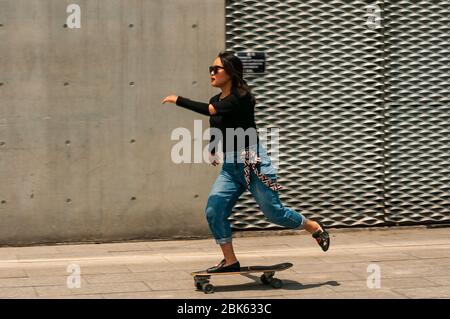 Una giovane donna cinese che pratica lo skateboard vicino al lungomare di fronte al Long Museum West Bund, Shanghai, Cina. Foto Stock