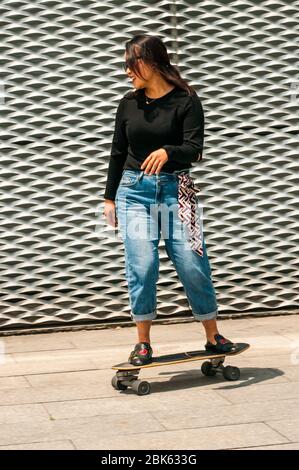 Una giovane donna cinese che pratica lo skateboard vicino al lungomare di fronte al Long Museum West Bund, Shanghai, Cina. Foto Stock