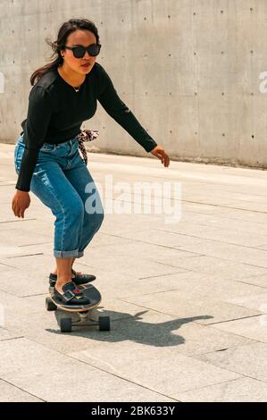 Una giovane donna cinese che pratica lo skateboard vicino al lungomare di fronte al Long Museum West Bund, Shanghai, Cina. Foto Stock