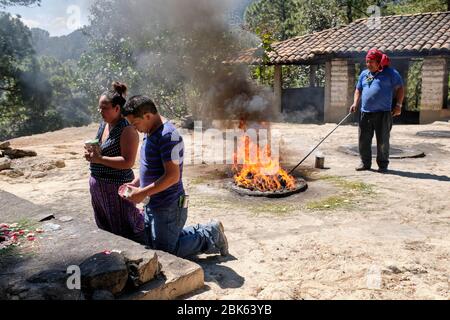 Sciamano che esegue una cerimonia di guarigione Maya per una famiglia sulla cima della collina Pascual Abaj, dove si trova la pietra sacra. Alcune fonti indicano Th Foto Stock