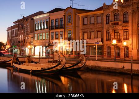 Aveiro, Portogallo - Aprile 2019: Barche tipiche di Moliceiro al canale d'acqua centrale e edifici in stile Art Nouveau, di notte. Foto Stock