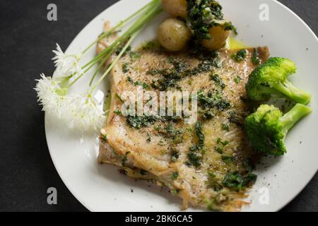 Un raggio, o skate, ala da un Thornback ray, Raja clavata, catturato nel canale inglese. E' stato fritto in olio e burro con aglio selvatico e mantello Foto Stock