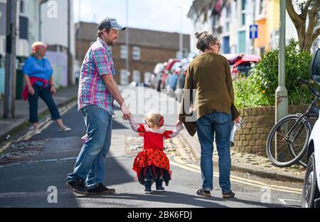 Brighton UK 2 maggio 2020 - i bambini delle famiglie nella zona di Elm Grove di Brighton hanno deciso di vestirsi e brevemente venire fuori sulla loro strada questa mattina osservando le distanze sociali il giorno che sarebbe stato il festival di Brighton Parade dei bambini durante la pandemia di Coronavirus COVID-19 crisi . La Parata dei Bambini è il tradizionale apritore del Festival di Brighton che è stato annullato quest'anno a causa del coronavirus . Credit: Simon Dack / Alamy Live News Foto Stock