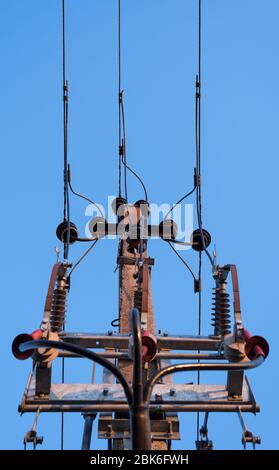 Torre di collegamento della linea ad alta tensione con isolatori visibili e cielo blu trasparente sopra Foto Stock
