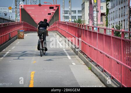 Un giovane uomo non identificato che pedala sul ponte di Williamsburg e corre il percorso da Brooklyn a Manhattan. Foto Stock