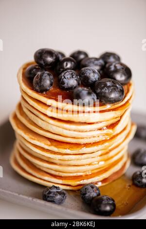 Pile di appetitose pancake con miele e more sul piatto al tavolo servito cucinato a casa o in bar per colazione Foto Stock