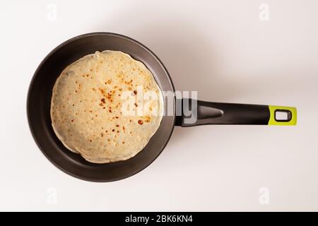 Vista dall'alto della padella nera con pancake appetitosi fatti in casa sul tavolo da cucina bianco con copyspace per la vostra nota sulla destra Foto Stock