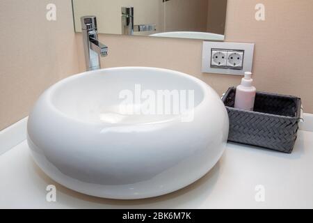 Lavabo rotondo ovale in ceramica bianca per il bagno. Bagno bianco con specchio rotondo e lavabo in ceramica bianca. Lavandino circolare in ceramica moderno Foto Stock