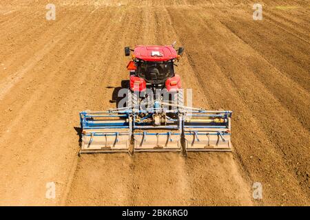 Pre-semina rullo di spianatura trattore in un campo, immagine aerea. Foto Stock