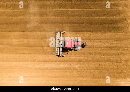 Pre-semina rullo di spianatura trattore in un campo, immagine aerea. Foto Stock