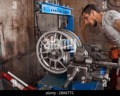 KHARKOV, UCRAINA - MARZO 2020, Service man sta ristrutturando e riparando il disco dell'automobile danneggiato in alluminio della lega alla scatola di servizio degli pneumatici. Foto Stock