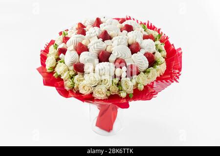 Bel bouquet creato da rose bianche, marshmallows e fragole mature rimangono in vaso su sfondo bianco. Foto Stock