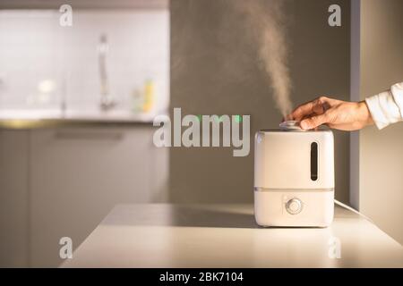 Accendi a mano il diffusore di olio aromatico sul tavolo a casa, il vapore dell'umidificatore dell'aria e lo spazio libero. Tecnologia a ultrasuoni, aumento di umidità dell'aria indoo Foto Stock