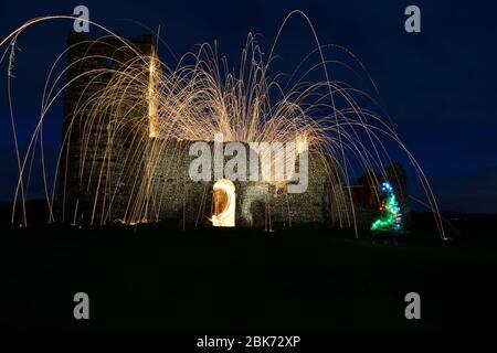 una vecchia chiesa derelict di notte con scintille e sentieri leggeri che esplodono da essa Foto Stock