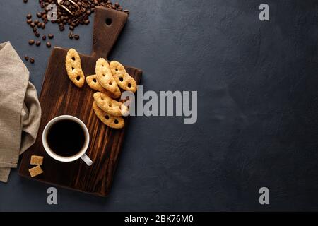 Tazza di caffè e pretzel francesi con zucchero sul tavolo da cucina. Vista dall'alto. Disposizione piatta. Sfondo in pietra nera. Vista dall'alto con spazio per le copie. Foto Stock