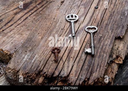 Vecchie chiavi di diverse dimensioni su tavole di legno intemperate rustiche Foto Stock