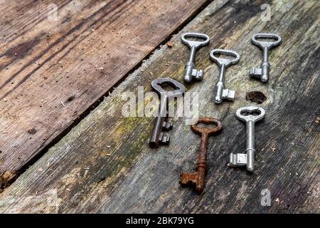 Vecchie chiavi di diverse dimensioni su tavole di legno intemperate rustiche Foto Stock