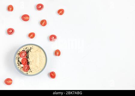 hummus composto da ceci in ciotole. su sfondo bianco decorato con pomodori. spazio per copia. piatto Foto Stock