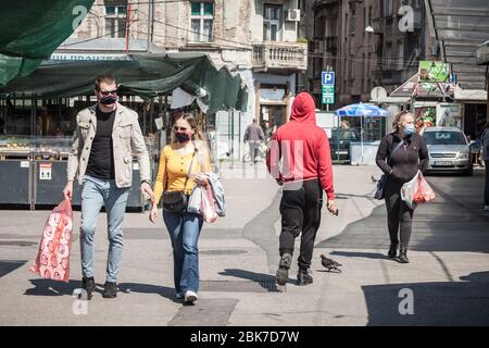 BELGRADO, SERBIA - 23 APRILE 2020: Giovani, una coppia, camminando e comprando generi alimentari in un mercato verde contadino di Belgrado indossando maschera protettiva Foto Stock