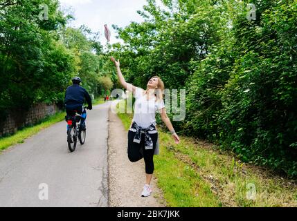 Una donna felice si toglie e lancia la maschera facciale in aria a causa della fine di un virus o pandemico e quarantena in una zona verde della città di ​​a Foto Stock