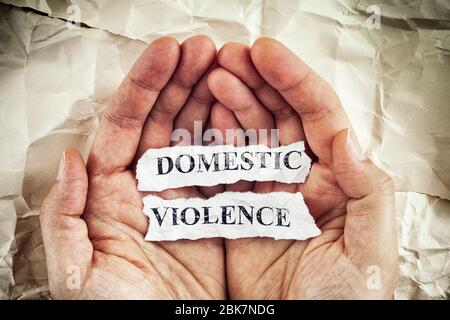 Violenza domestica. Donna che tiene pezzi di carta strappati con le parole violenza domestica scritte su di loro nelle sue palme. Immagine concettuale. Primo piano. Foto Stock