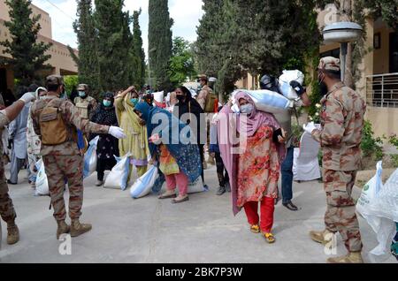 I funzionari dell'esercito stanno distribuendo i beni di soccorso tra le persone bisognose durante la cerimonia di distribuzione di razione da parte dell'esercito pakistano durante il blocco nazionale imposto dal governo a causa dell'aumento dei casi di coronavirus, come misura preventiva contro la diffusione del Coronavirus (COVID-19), a Quetta il sabato 2 maggio 2020. Foto Stock