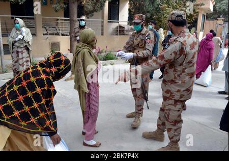 I funzionari dell'esercito stanno distribuendo i beni di soccorso tra le persone bisognose durante la cerimonia di distribuzione di razione da parte dell'esercito pakistano durante il blocco nazionale imposto dal governo a causa dell'aumento dei casi di coronavirus, come misura preventiva contro la diffusione del Coronavirus (COVID-19), a Quetta il sabato 2 maggio 2020. Foto Stock