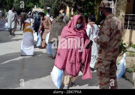 I funzionari dell'esercito stanno distribuendo i beni di soccorso tra le persone bisognose durante la cerimonia di distribuzione di razione da parte dell'esercito pakistano durante il blocco nazionale imposto dal governo a causa dell'aumento dei casi di coronavirus, come misura preventiva contro la diffusione del Coronavirus (COVID-19), a Quetta il sabato 2 maggio 2020. Foto Stock