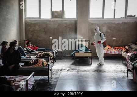 Jisr al Shughur, Siria. 02 maggio 2020. Un uomo indossa un equipaggiamento protettivo mentre spruzza disinfettante all'interno di un centro di isolamento sanitario che è stato istituito ai confini siriano-turchi per collocare le persone provenienti dalla Turchia a Idlib come misura preventiva contro la diffusione della malattia di coronavirus (COVID-19). Il centro è controllato da un team medico addestrato in tutte le misure da prendere per trattare con gli espatriati, in quanto il centro ha ricevuto finora più di 600 persone e il periodo di isolamento è di 15 giorni. Credit: ANAS Alkharboutli/dpa/Alamy Live News Foto Stock