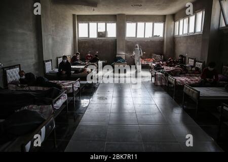 Jisr al Shughur, Siria. 02 maggio 2020. Un uomo indossa un equipaggiamento protettivo mentre spruzza disinfettante all'interno di un centro di isolamento sanitario che è stato istituito ai confini siriano-turchi per collocare le persone provenienti dalla Turchia a Idlib come misura preventiva contro la diffusione della malattia di coronavirus (COVID-19). Il centro è controllato da un team medico addestrato in tutte le misure da prendere per trattare con gli espatriati, in quanto il centro ha ricevuto finora più di 600 persone e il periodo di isolamento è di 15 giorni. Credit: ANAS Alkharboutli/dpa/Alamy Live News Foto Stock