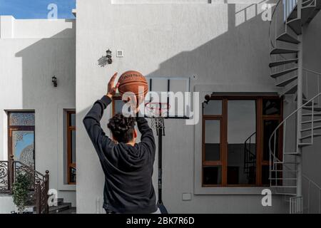 Giovane uomo che gioca a basket all'aperto nel cortile tiro di una palla al bordo | immagine naturale | Slam Dunk Foto Stock