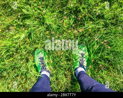 Atleta che esce per gli sport all'aperto all'inizio della fine del coronavirus. Persona con l'abito per andare a correre con l'erba verde di t Foto Stock