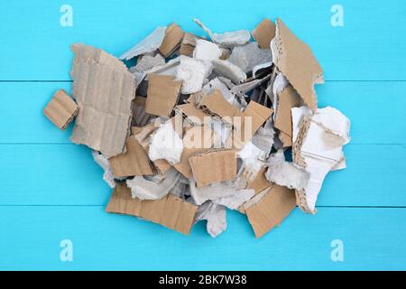 Pezzi di cartone su fondo di legno blu. Riciclaggio della carta di scarto. Pezzi di scatole di cartone, carta impilata in una vista dall'alto di pile. Foto Stock