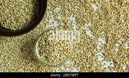 Grano saraceno verde in una ciotola trasparente di vetro su uno sfondo marrone. Alimenti sani. Cibo vegetariano non fritto, crudo e biologico. Il concetto di un sano e. Foto Stock